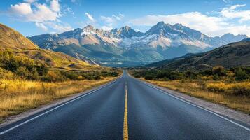 Majestic Mountain Range Frames a Long Asphalt Road Stretching Into the Horizon During Bright Daylight photo