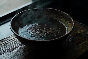 Steaming Bowl of Dark Noodles on Rustic Wood Surface A Close-Up Image of a Traditional Dish. photo