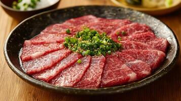 Thinly Sliced Raw Beef Arranged on a Dark Plate with Green Onions and Sesame Seeds. photo