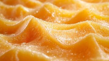 Close Up of a Textured, Golden Yellow Substance with Water Droplets. A Detailed Macro Photograph of a Viscous, Wavy Surface. photo