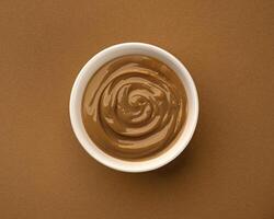 Boiled condensed milk, bowl of melted caramel cream, top view photo
