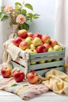 A rustic crate overflows with crisp red and green apples, nestled on a soft knit cloth beside delicate pink flowers, with a bee flying nearby photo