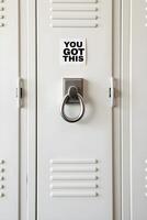 light gray metal locker features a silver handle and a white sticker that boldly states YOU GOT THIS photo