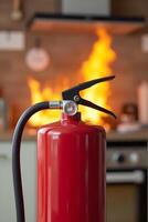 Single red fire extinguisher stands prominently in the foreground, sharply focused, while flames erupt from a stove photo