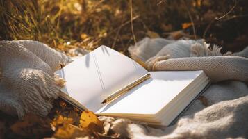 serene scene featuring open notebook with blank pages resting on cozy blanket surrounded by autumn leaves, inviting creativity and reflection photo