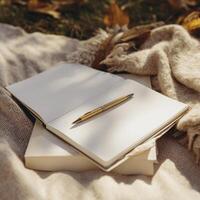 blank notebook with white pages and gold pen resting on top, surrounded by autumn leaves, evokes sense of creativity and inspiration photo