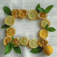 Fresh lemons and mint leaves arranged in decorative frame on white background, creating vibrant and refreshing display photo