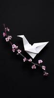 White origami bird and blossom branch convey sense of peace, like wish taking flight against darkness. symbol of hope and beauty photo