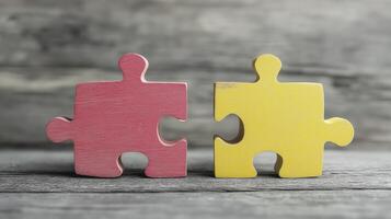 Two puzzle pieces, one red and other yellow, symbolize connection and teamwork, set against rustic wooden background photo