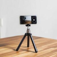 smartphone mounted on tripod, positioned on wooden table, capturing reflection in minimalist setting photo