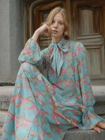 model wearing turquoise dress with fish pattern, showcasing elegance and style. dress features bow tie collar and flowing fabric photo