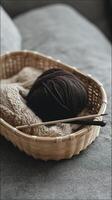 cozy bamboo basket holds ball of dark yarn and knitting needles, perfect for crafting and relaxation photo