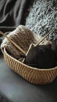 cozy bamboo basket filled with dark yarn, knitting needles, and soft knitted blanket on sofa, creating warm crafting atmosphere photo