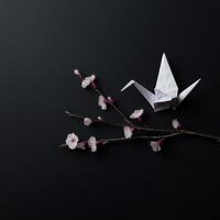 White origami bird and cherry twig evokes sense of peace on black background, minimalist and elegant composition that feels serene and hopeful photo