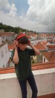 A child joyfully enjoys music on a rooftop, taking in the beautiful scenery around video