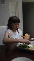 A Child Delightfully Enjoying a Big Burger Along with Fresh Salad at the Dining Table video
