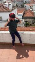 A Child Happily Enjoying Music While Sitting on the Rooftop with a Beautiful Scenic View video