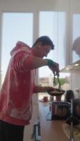 A Young Chef Enthusiastically Cooking in a Modern Kitchen While Wearing a Colorful Sweatshirt video
