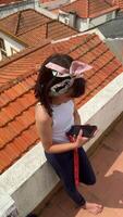 A young girl enjoying her time on a rooftop while using her smartphone in a beautiful urban setting video