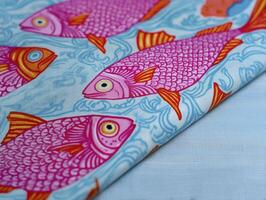 Vibrant fabric featuring colorful fish patterns in pink and orange against blue background, perfect for creative projects photo