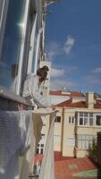 A Person Happily Hanging Laundry on Their Balcony Under a Beautiful Clear Blue Sky video