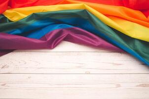 Top view of the rainbow flag or LGBTQ flag on a wooden table. photo