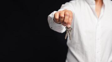 Hand of a businessman or real estate agent with keys from a new house hanging on the finger photo