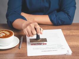 Businessman stamped for rejection on a document while sitting at the table in the office photo
