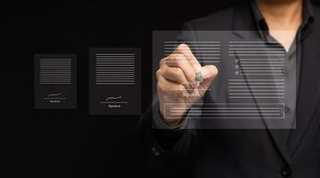 Close-up of a businessman uses a pen to sign electronic documents on a virtual screen while standing on a black background photo