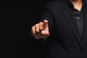Businessman in a suit finger pointing while standing on a black background in the office photo
