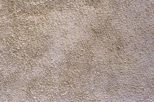 A wall with a textured surface. The wall is tan in color. The texture is rough and uneven. photo