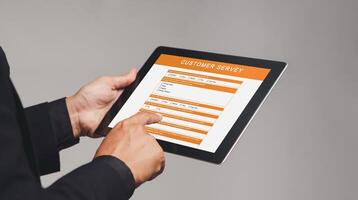 Businessman holding a tablet with a customer survey form while standing on a gray background photo