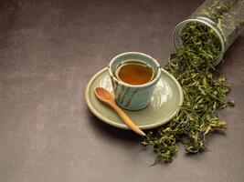 Dry cannabis leaf tea outside a box and marijuana tea cup on a table. photo