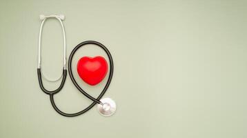Cardiology specialist. Top view of a stethoscope and a red heart shape on a green background photo