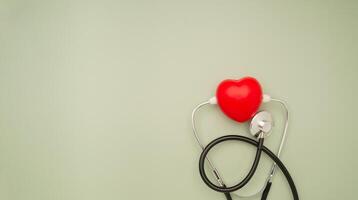Cardiology specialist. Top view of a stethoscope and a red heart shape on a green background. Space for text. photo