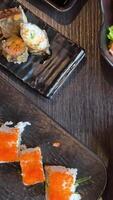 Top View of Various Kind of Sushi Pieces with Camera Motion. Fresh Japanese Sushi, Asian Cuisine Concept. People it Picking up. Placed on Black Stone Table. Camera Placed on Motion Control System. video