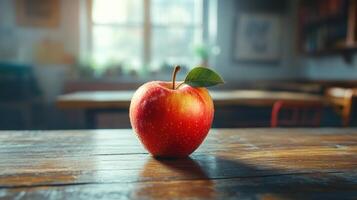 An apple sitting on a wooden table in front of a classroom photo