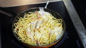 Preparation of a delicious dish in frying pan. Cooking and stirring the spaghetti with white sauce in the frying pan. Close-up. video