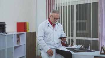 Confident family therapist working online. Doctor in white gown consulting people via internet using mobile phone in the office. video
