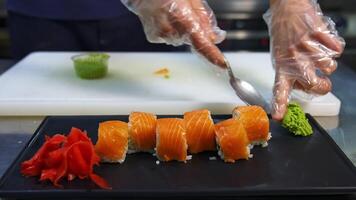 Professional chef hand decorate sushi roll on a serving plate to custom. Chef preparing delicious sushi menu fish with rice in japanese restaurant. video