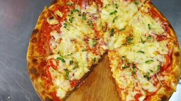 Fresh pizza spinning on the table. Delicious pastry with melted cheese, tomatoes and meat in pizzeria. Well baked pizza without one portion on table. video