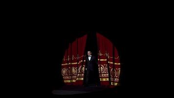 Actor appears on stage. Red curtains open and a theater host in suit comes on the scene on dark background in light spot. video