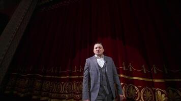 Actor man speaking and dancing on stage. Man in suit on stage in front of empty audience. Orbiting shot. video