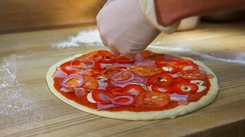 Pizza preparation.Hands putting slices of onions on pizza dough on table. Process of making pizza. Chef prepares filling for delicious pizza. video