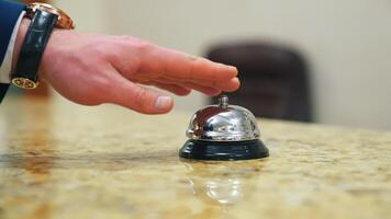 Calling the receptionist. Hand of a tourist in the reception of a hotel presses the bell button. Close-up. video
