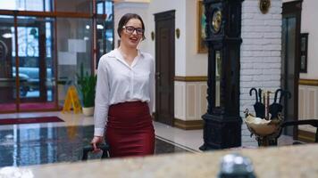 Charming lady with suitcase in the reception lobby. Girl approaching hotel reception to take the key. Portrait of gorgeous woman pressing bell button at reception desk. video