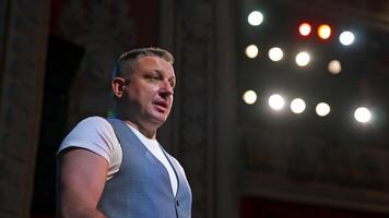 Man on the theater stage. Middle-aged man dressing on medical mask during coronavirus in spotlights. Side view. video
