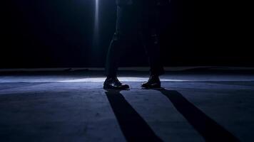 Legs of a dancer in move. Man in trousers and shoes dancing on the stage in dark scenic light. video