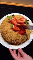 Whole honey cake topped with vibrant strawberries, cake placed on white plate ready to slice, cake texture crumbly and golden, cake ideal for rustic food visuals. Classic honey dessert, fresh berries video