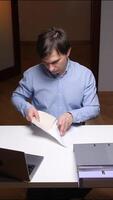 vertical Office worker opening envelope with documents at desk with laptop and files video
